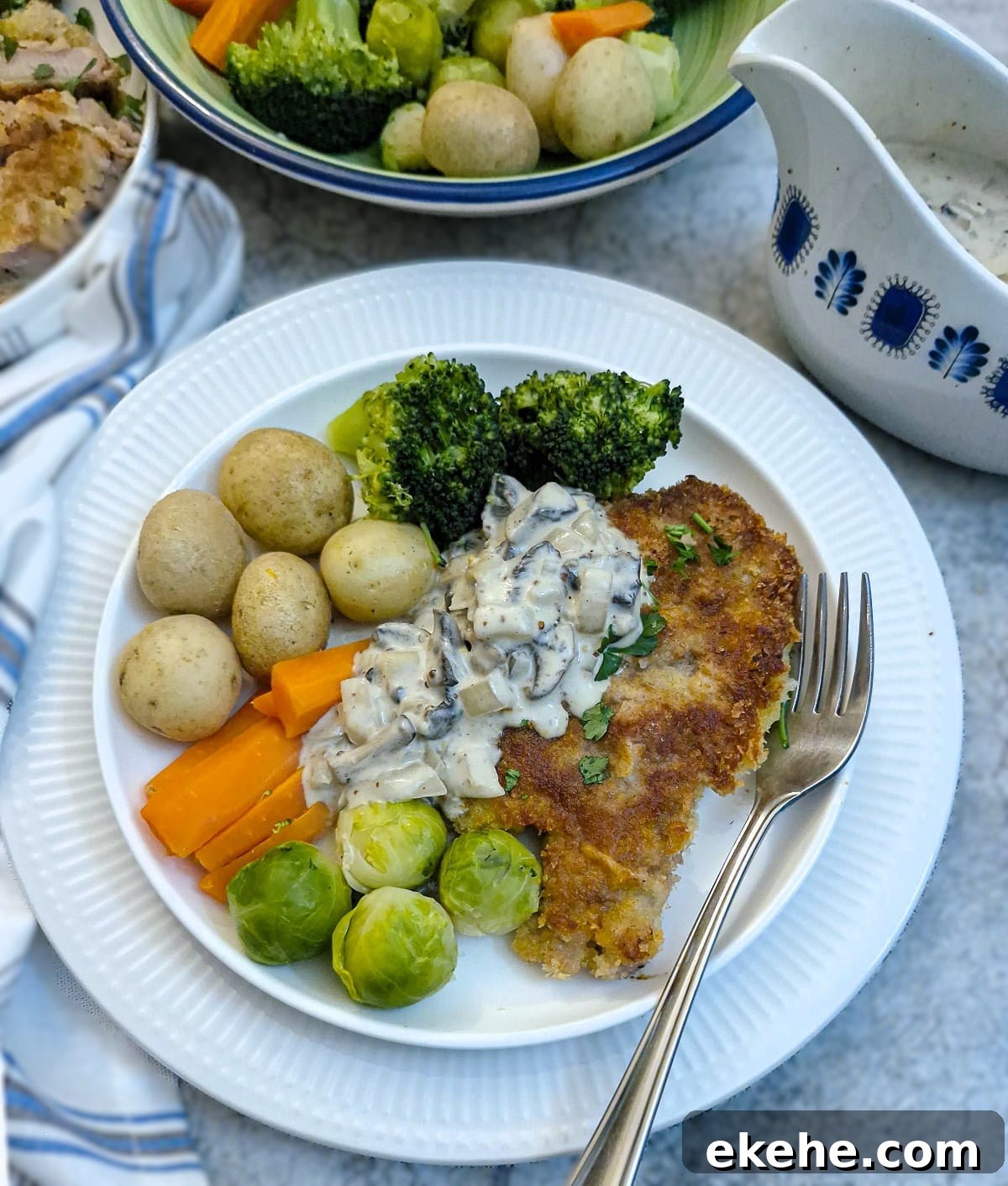 Crispy Crumbed Pork Chops with Mushroom Mustard Sauce 3 A crumbed pork chop on a plate with vegetables and potatoes. The chop has been partially covered with creamy mushroom mustard sauce.