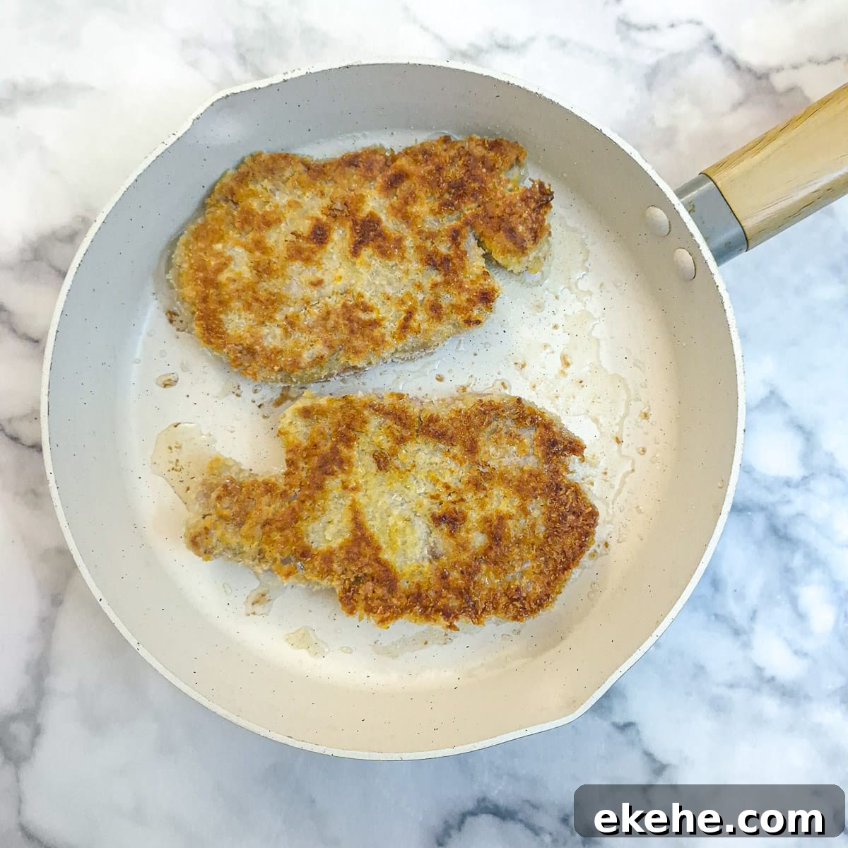 Crispy Crumbed Pork Chops with Mushroom Mustard Sauce 10 2 crumbed pork chops browning in a frying pan.