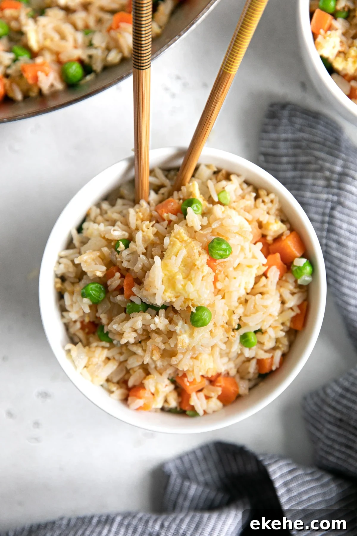 Overhead image of a small white serving bowl filled with veggie filled fried rice.