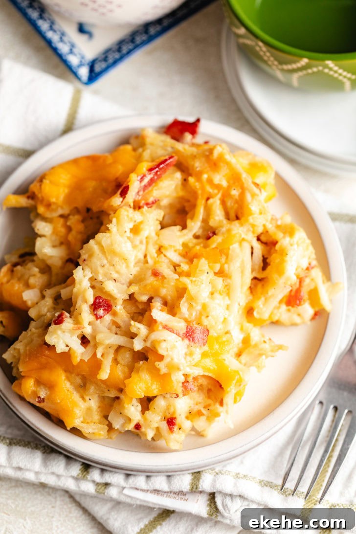 Overhead view of cheesy shredded potato bake on a plate with a striped kitchen towel.
