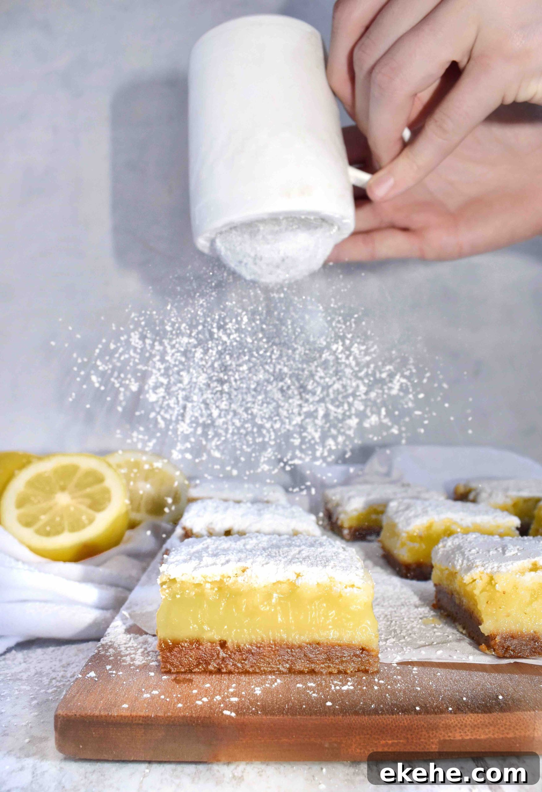 powder sugar being shaken over lemon bars with gingersnap crust