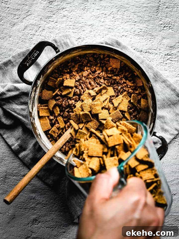 mixing Golden Grahams into melted marshmallow and cocoa Krispies to make s'mores Rice Krispie treats