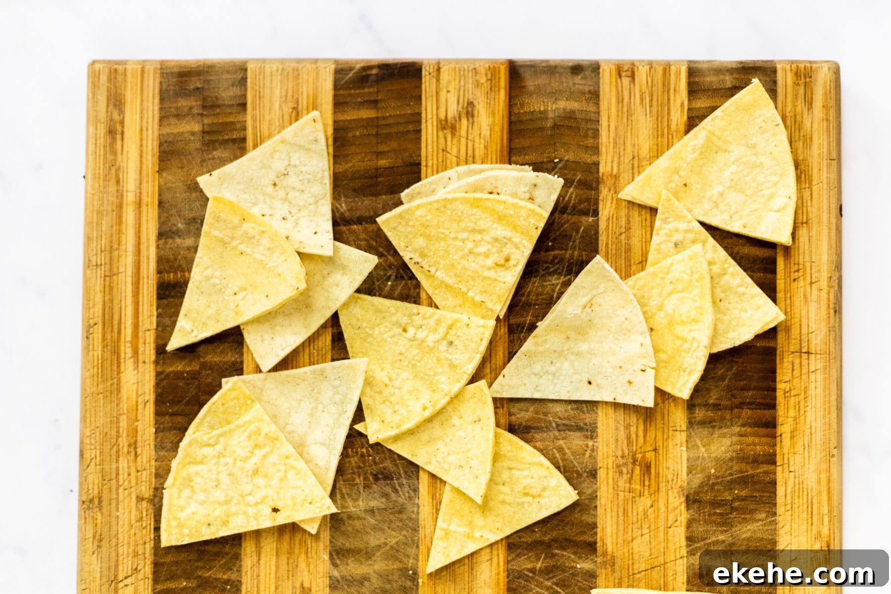 corn tortillas cut into triangles on a cutting board.
