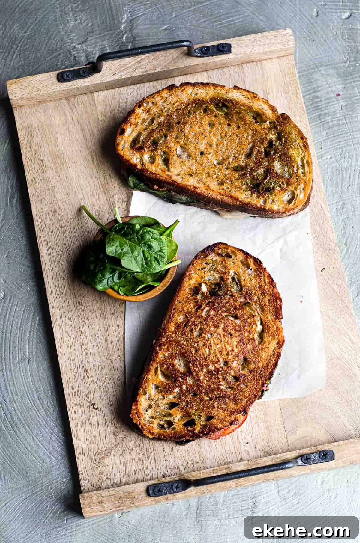A wood cutting board with two grilled cheese sandwiches laying on it