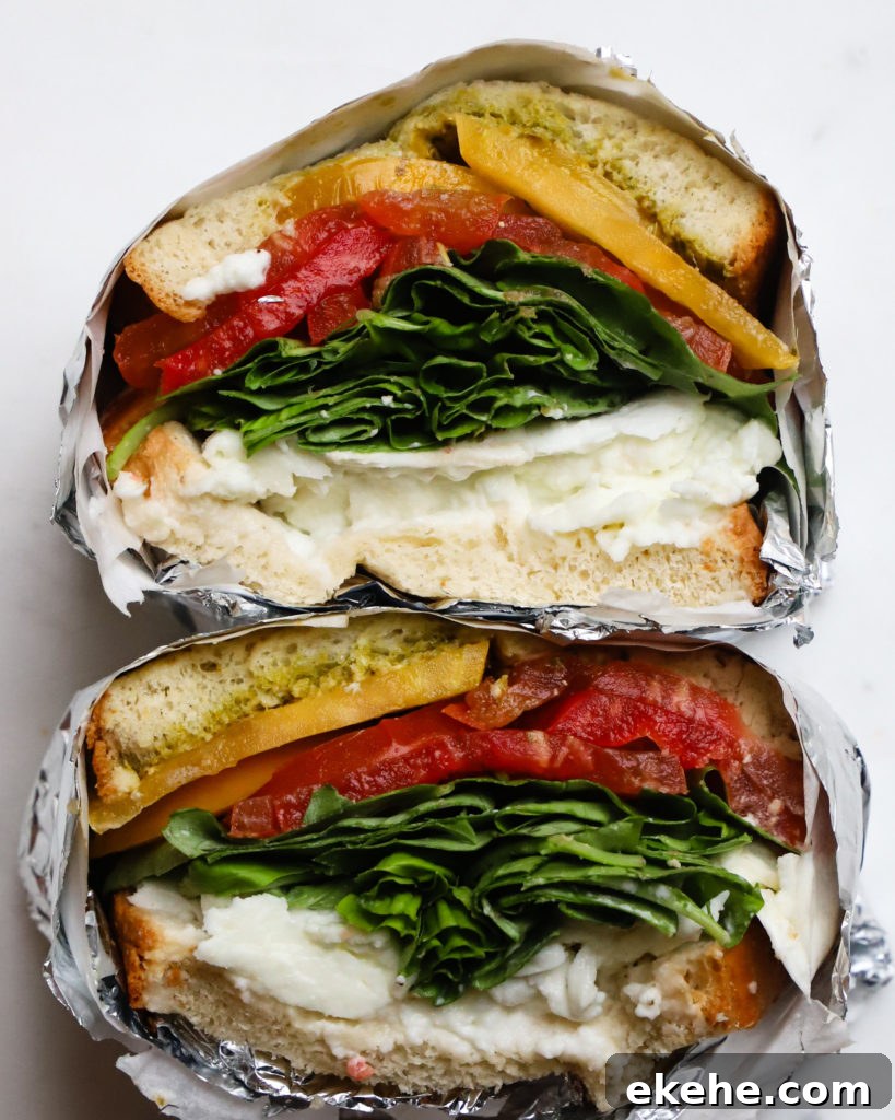 Heirloom tomato caprese sandwich with mozzarella, fresh greens, and pesto in foil.