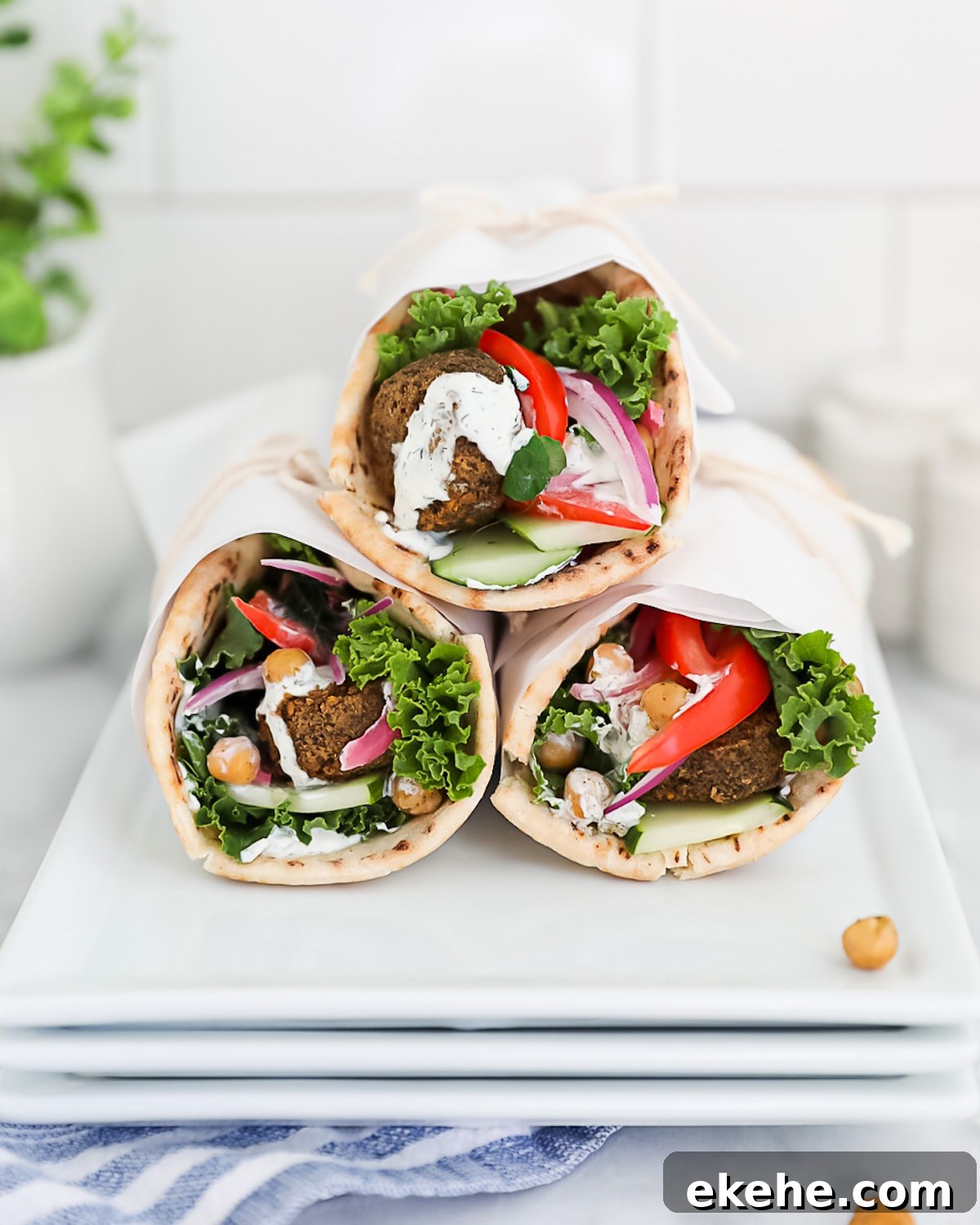 3 vegan gyros filled with fresh veggies, falafel, chickpeas, and a vegan tzatziki.