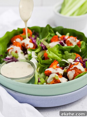 A green bowl filled with cauliflower lettuce wraps with a drizzle of vegan ranch dressing on top.