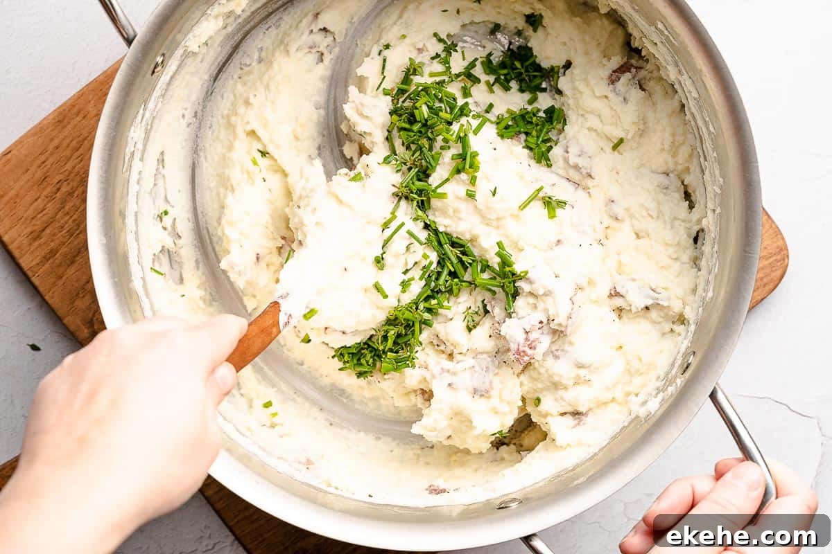 herbs being stirred into pot of mashed potatoes