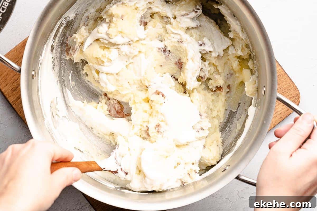 sour cream being stirred into mashed potatoes