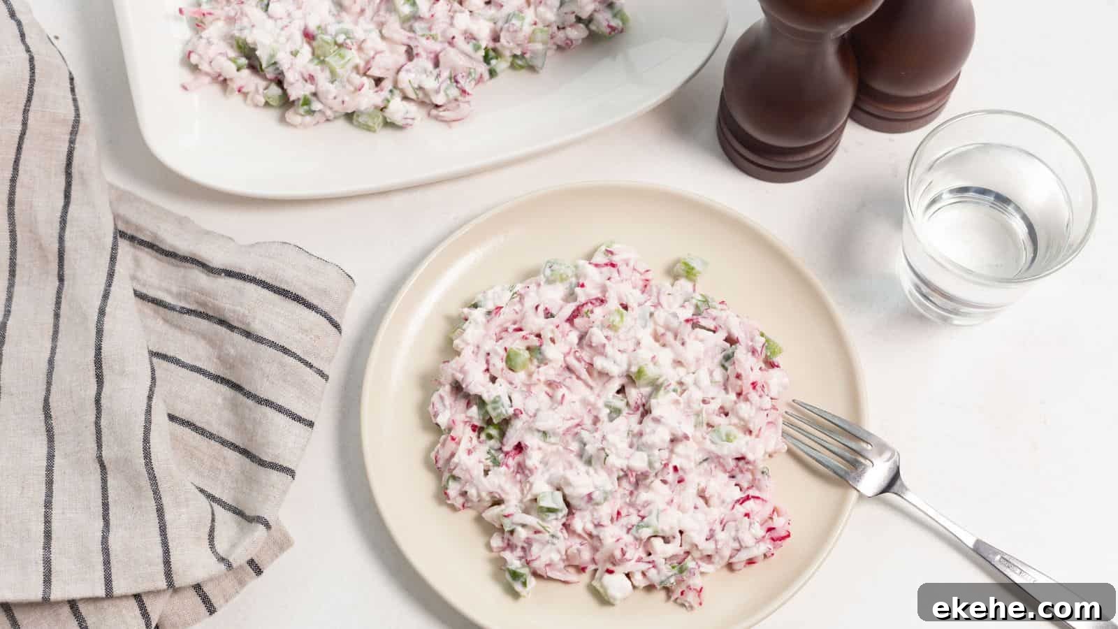 A plate of radish salad with diced celery and a creamy dressing, accompanied by a glass of water and salt and pepper shakers.