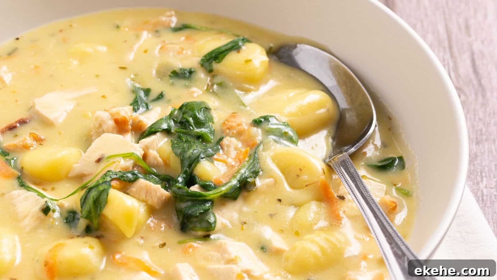 A bowl of chicken and spinach soup with a spoon.