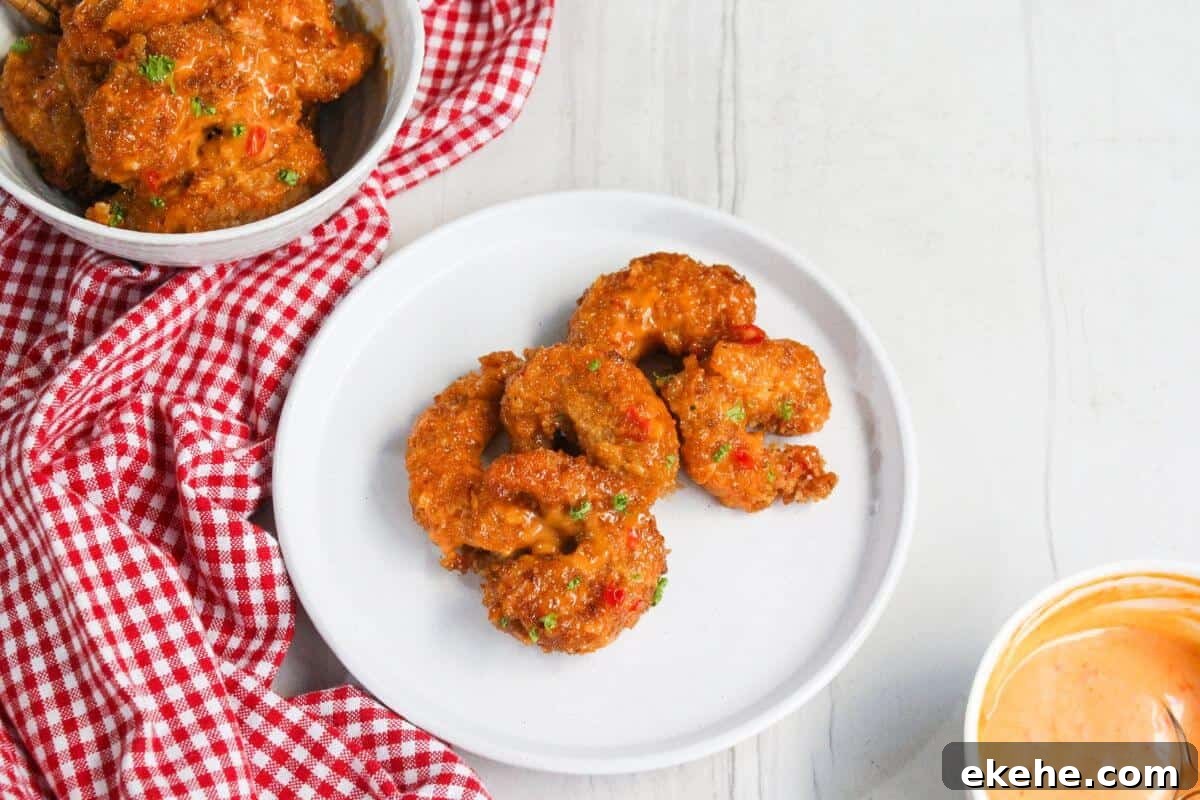 Fried shrimp on a plate next to a bowl of sauce.