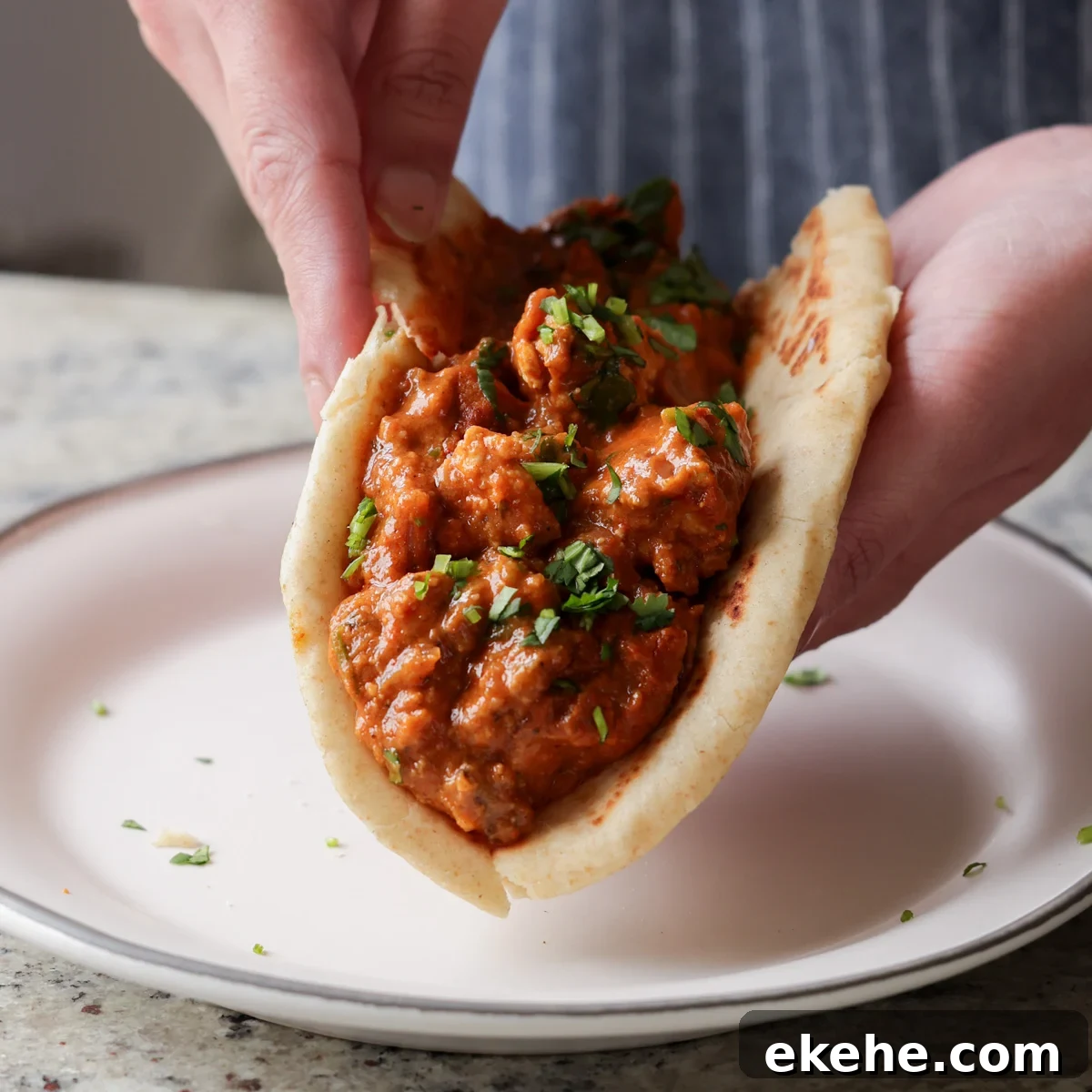 hands holding chicken angara folded into a piece of flatbread