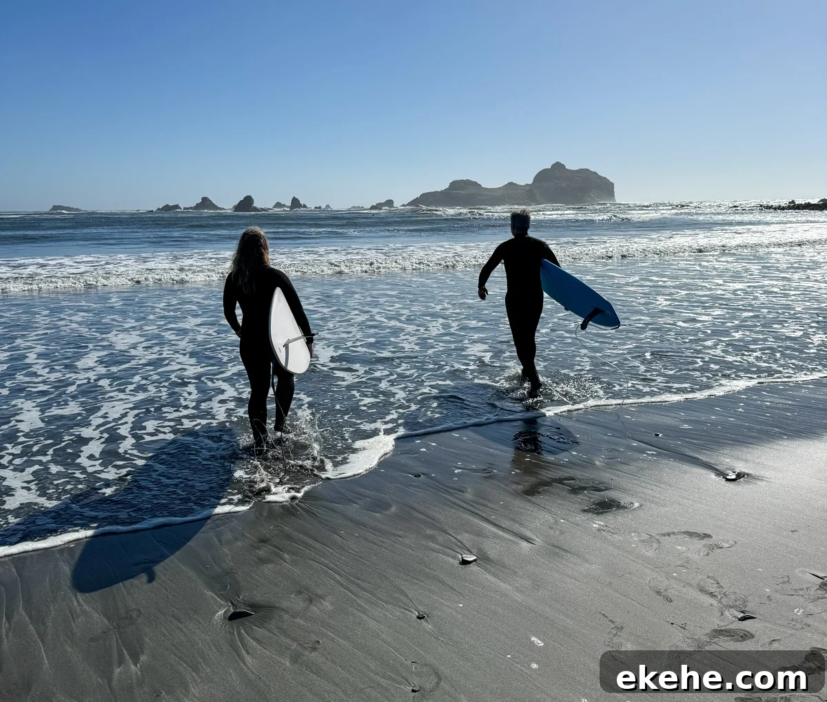father and daughter heading out to surf with a sunny blue sky
