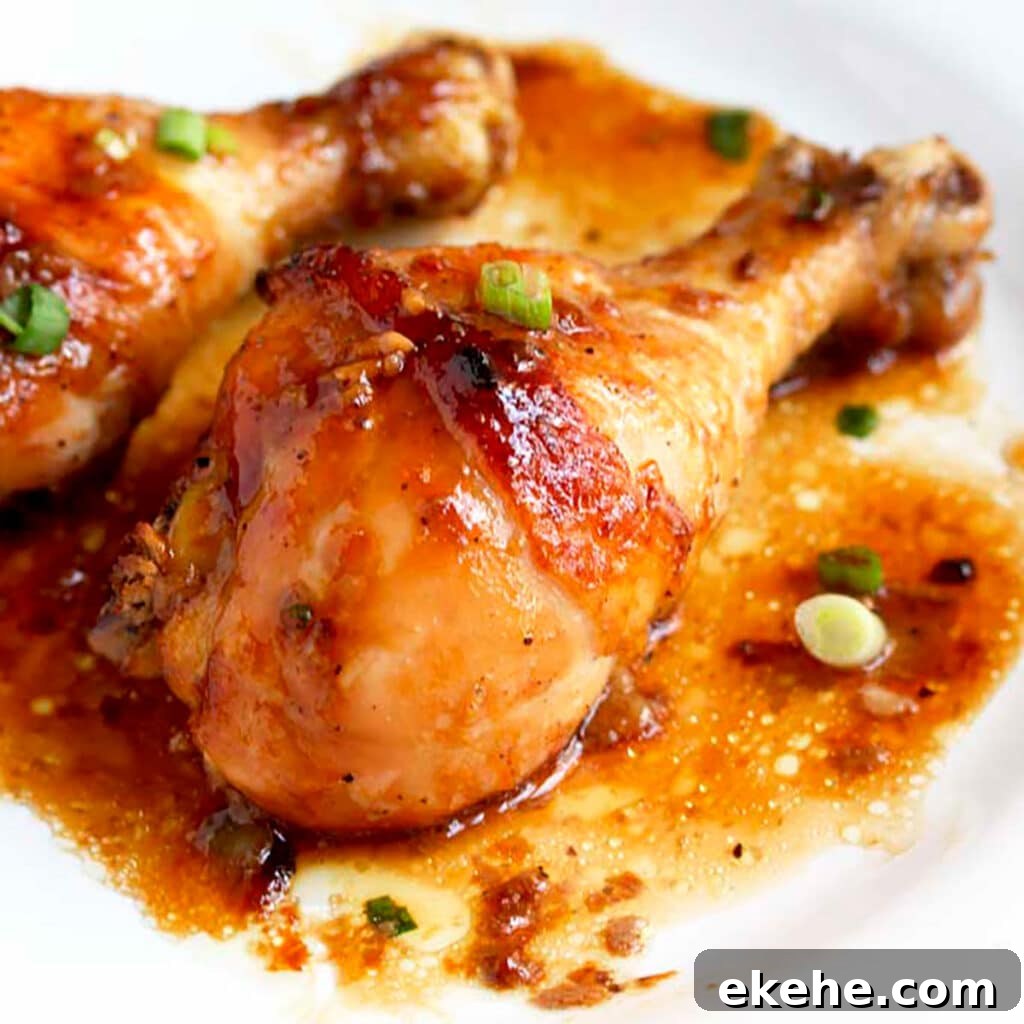 Golden brown baked chicken drumsticks with sweet and savory honey soy sauce on a white dinner plate