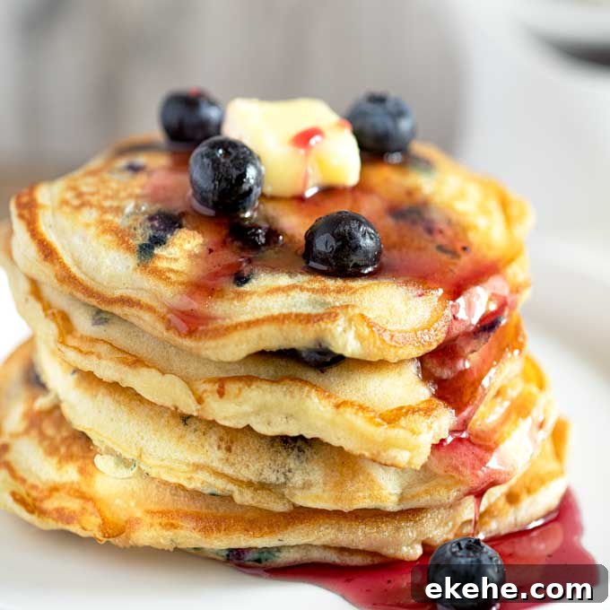 Fluffy Blueberry Pancakes Stacked up and drizzled with blueberry syrup.