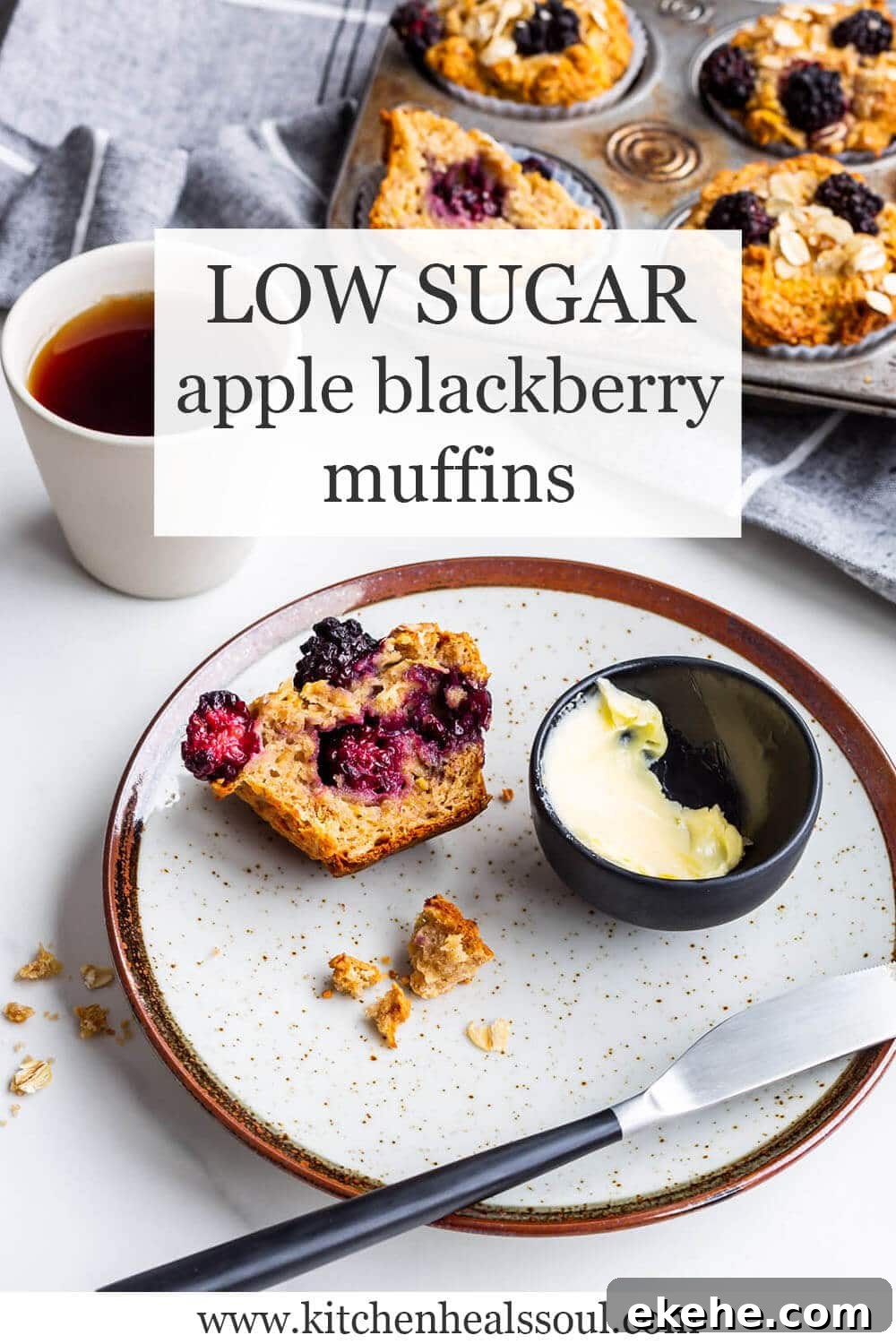Low sugar apple blackberry muffins with a vintage muffin pan of baked muffins in the background, a cup of black tea, and a speckled ceramic plate with half a muffin and a dish of butter + knife