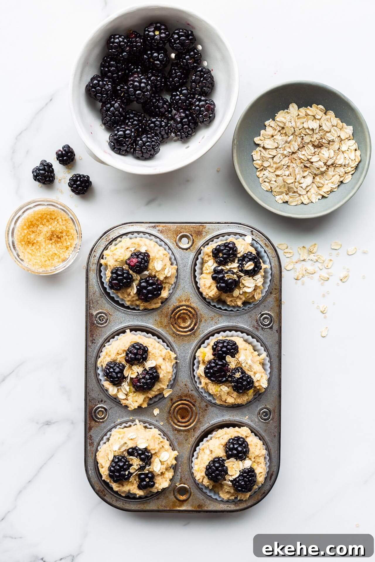 Finishing apple blackberry muffins placing blackberries, oats, and turbinado sugar on top before baking