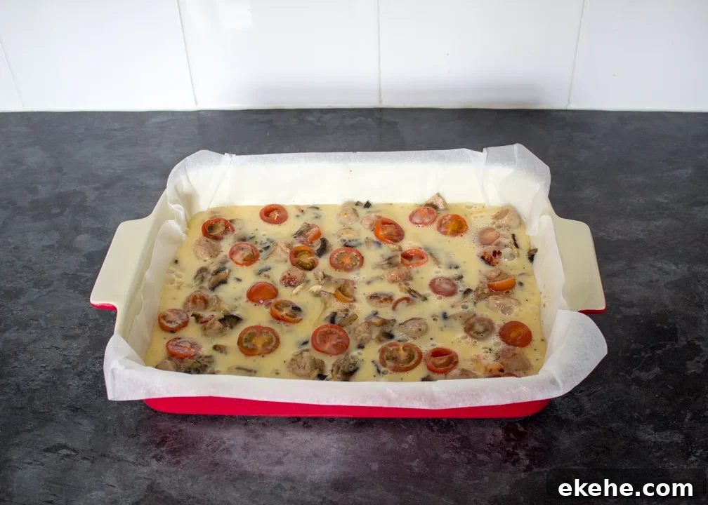 Uncooked full English frittata in a lined ovenproof dish
