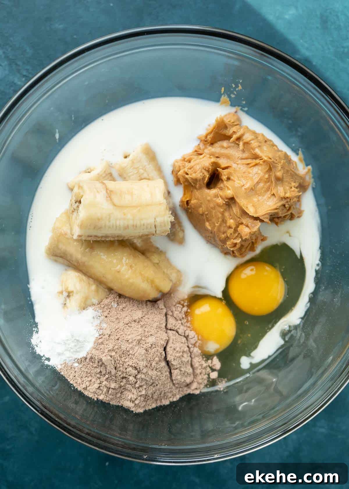 protein powder, bananas, eggs, milk, and nut butter in a glass bowl