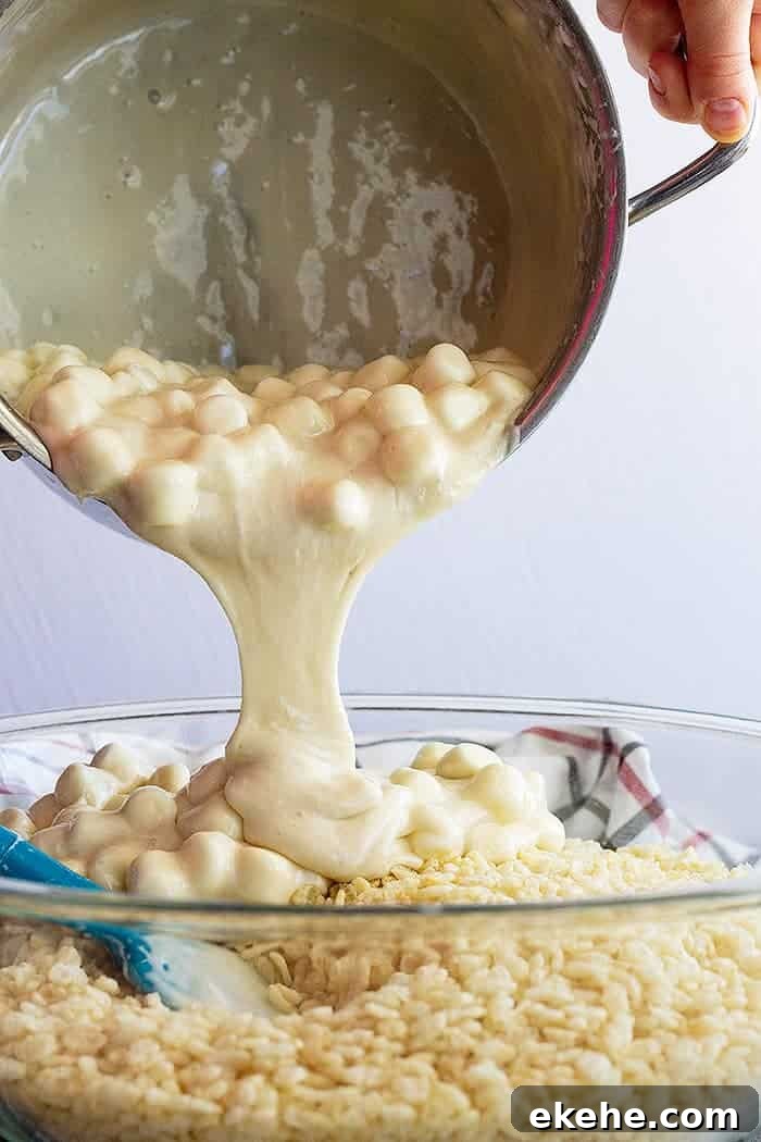 pouring marshmallow mixture into rice krispies