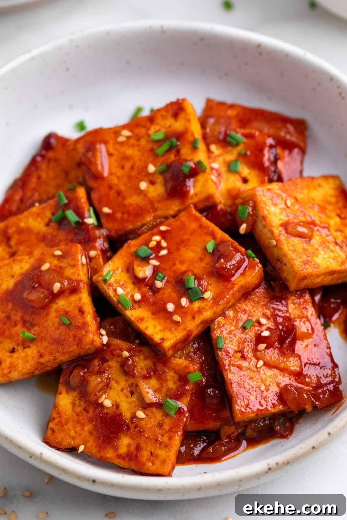 Spicy tofu garnished with sesame seeds and chives.