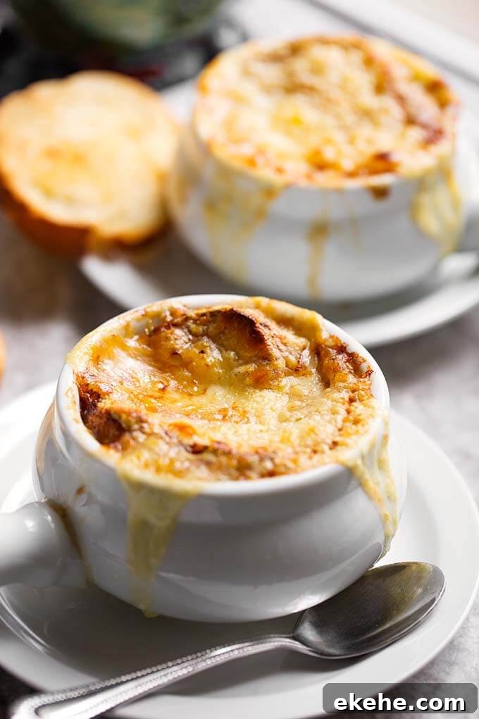 French Onion Soup with melted cheese and small slice of toasted bread on white plates