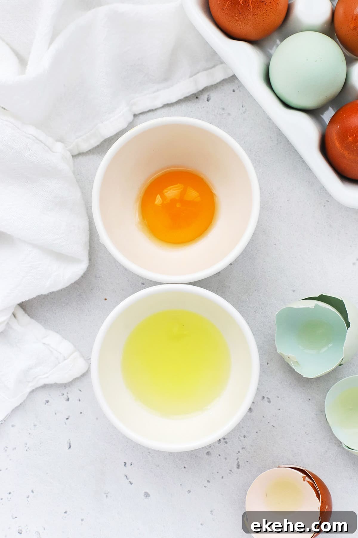 Overhead view of a separated egg, with the yolk in one bowl and the white in another bowl