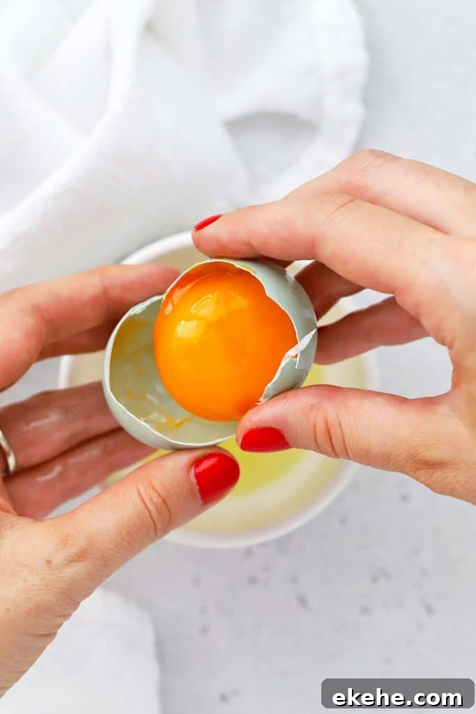 Overhead view of using an egg shell to separate egg yolks and egg whites