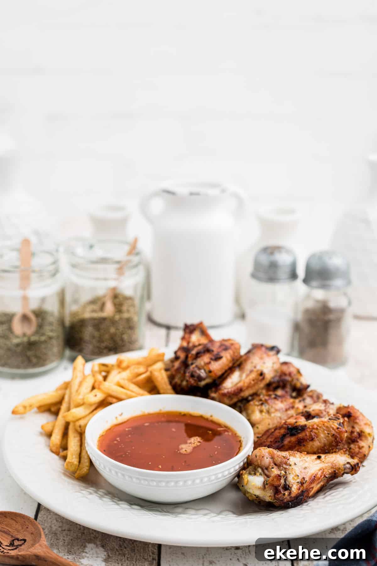 side view of a plate of chicken wings with french fries and cajun butter sauce.