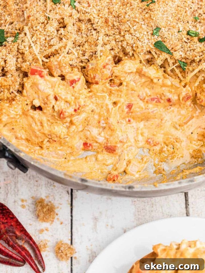 skillet of crawfish dip with breadcrumbs on top, with cream cheese. Crawfish in the corners.
