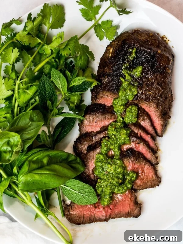 Asian marinated flank steak, spicy Asian chimichurri steak with fresh herbs on a white plate