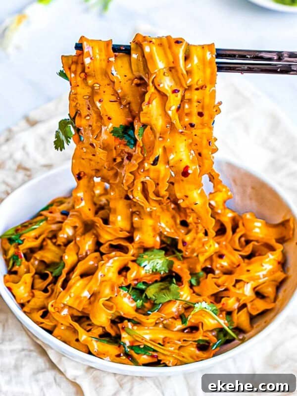 Spicy Szechuan noodles with garlic chili oil in a white bowl with chopsticks