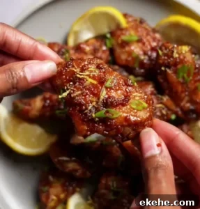 Korean Asian chicken wings with a sweet and tangy sauce garnished with green onions and a side of ranch dressing.