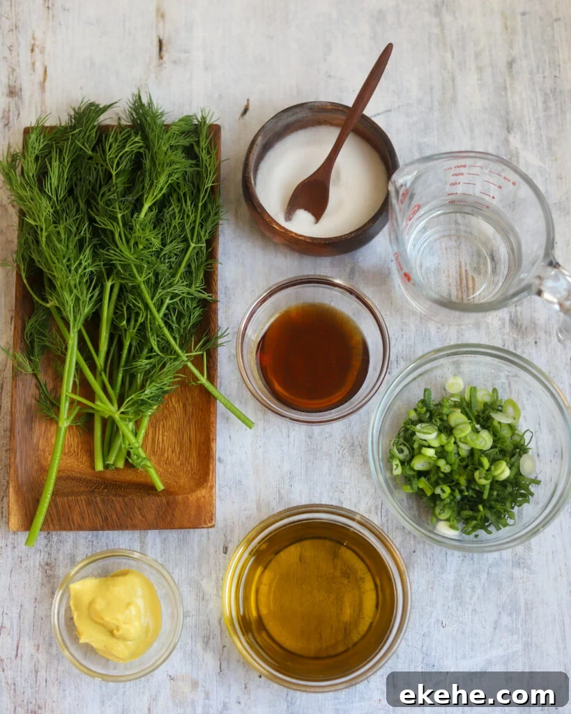 overhead view of ingredients for Dijon vegan salad dressing in small bowls containing vinegar, olive oil, maple syrup, mustard, salt and green onions. The bowls are sitting on a gray surface along with a wood cutting board filled with fresh dill.