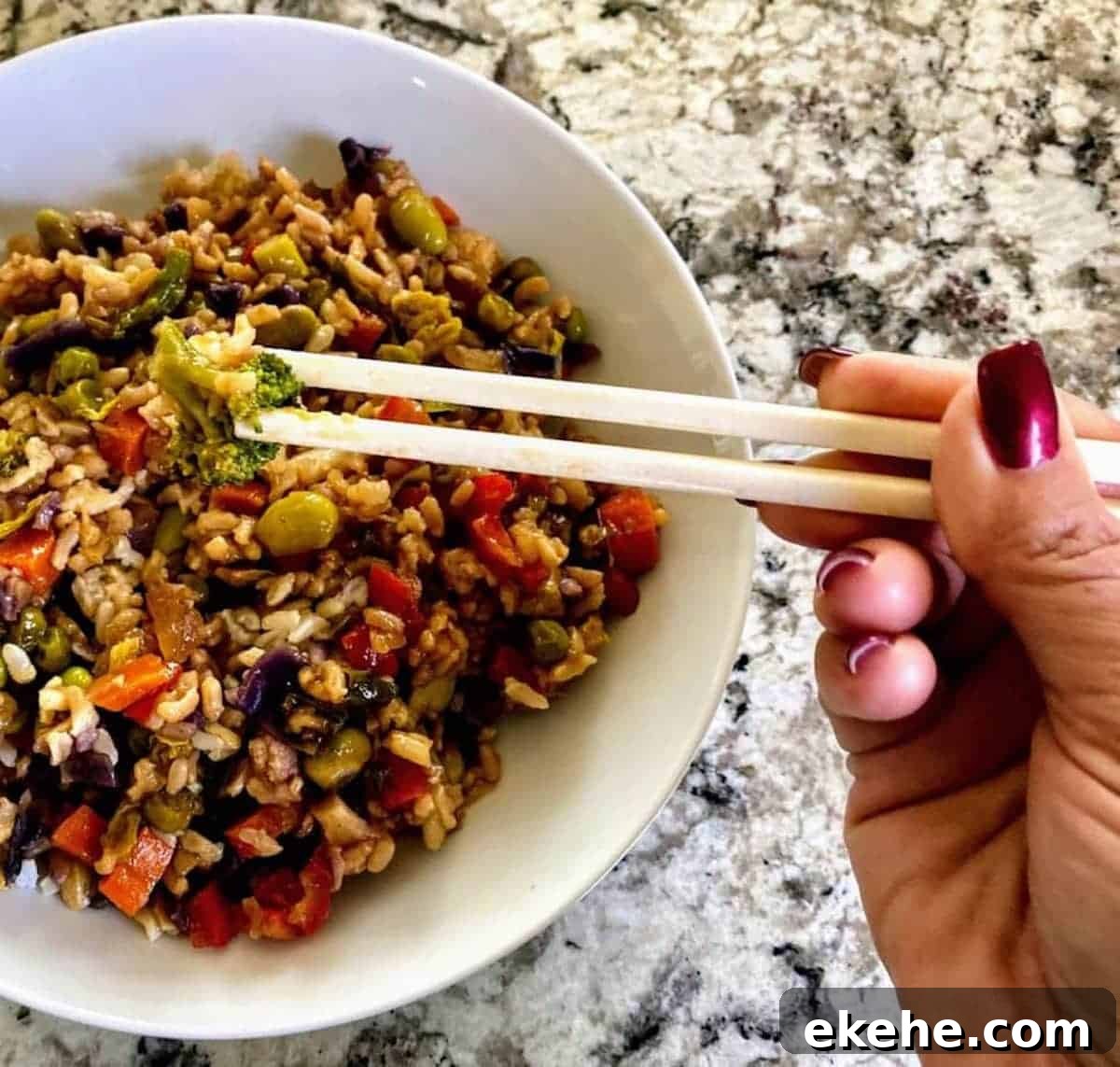 I am eating vegan vegetable fried rice with chop sticks.