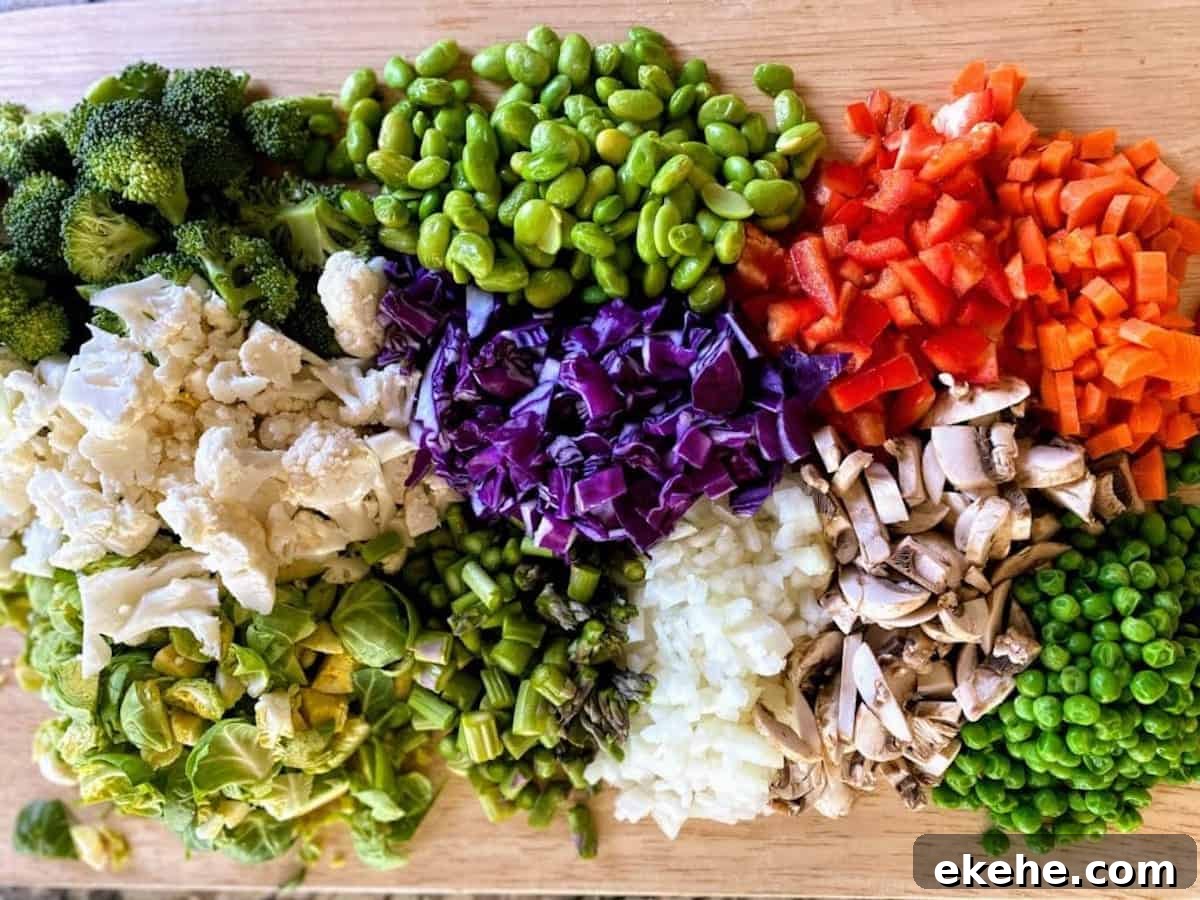 Vegetables cut on cutting board: broccoli, cauliflower, brussels sprouts, cabbage, edamame, red bell pepper, peas, mushrooms, onions, and asparagus.