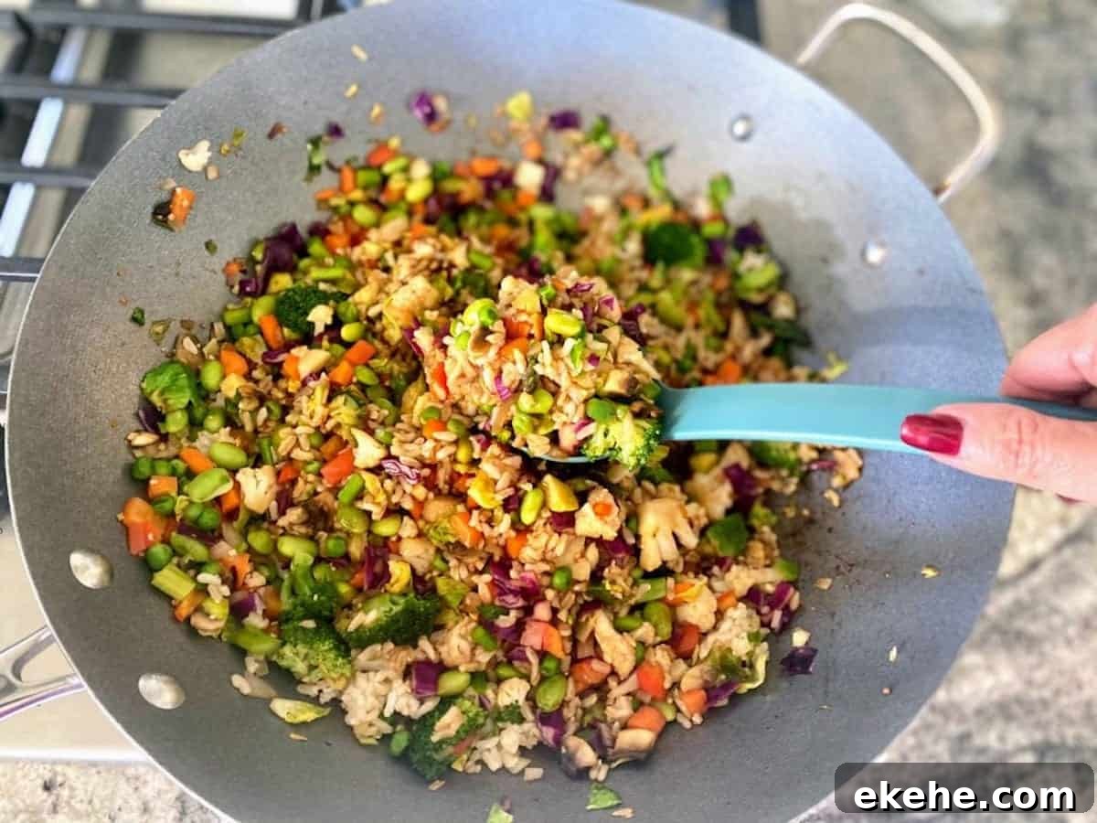 Spoon serving vegan vegetable fried rice from a wok.