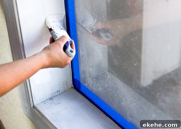 painting primed trim white with window taped off with blue painters tape