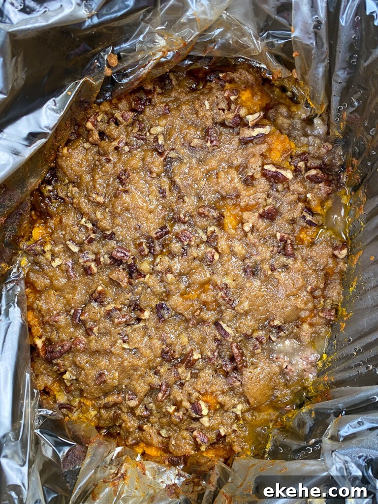 Layer of brown sugar, butter and pecan candy topping on the best mashed sweet potato casserole in a crock pot