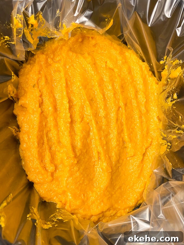 Loaded sweet potato casserole smoothed out in a large black crock pot with a liner