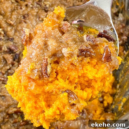 Spoonful of pecan and brown sugar crusted sweet potato casserole over top of a crock pot full