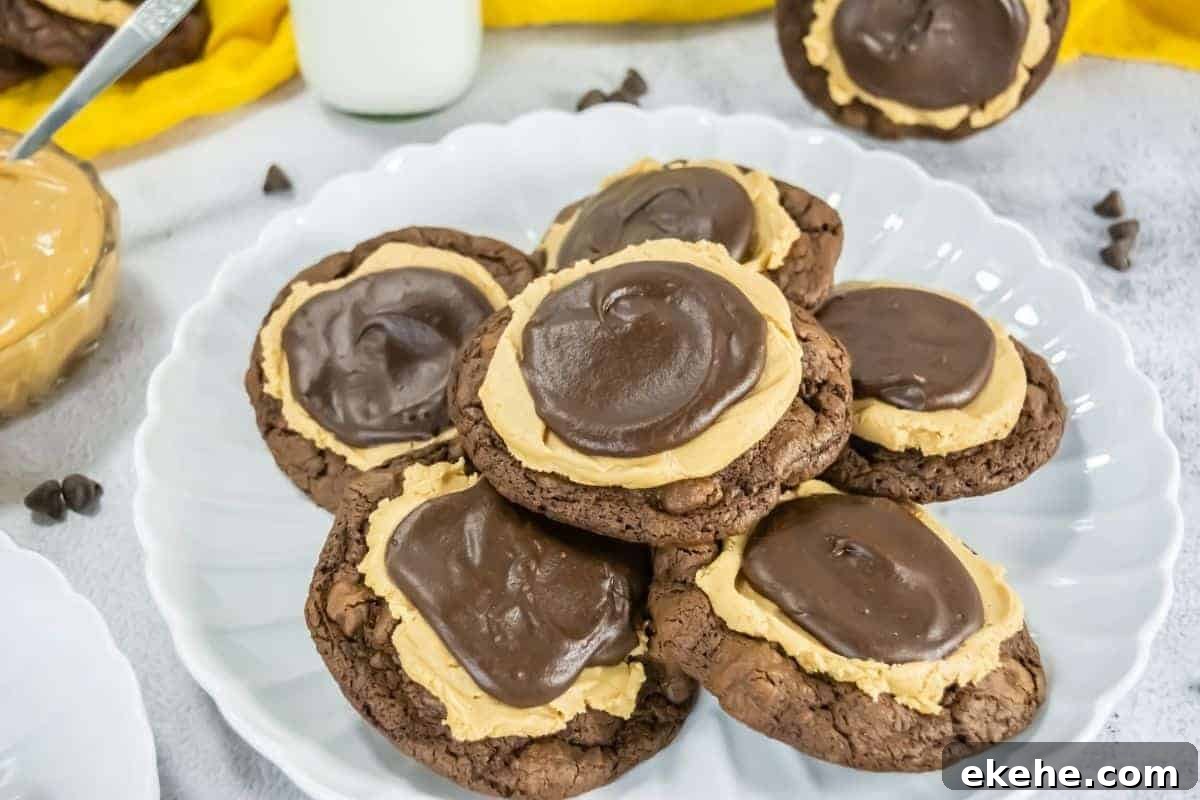 A plate with several Crumbl Copycat Buckeye Brownie cookies topped with a layer of peanut butter and a swirl of chocolate frosting.