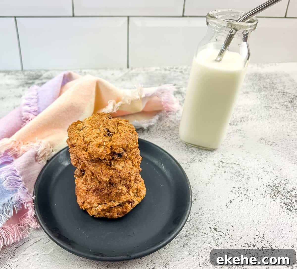 Oatmeal raisin cookies on a plate next to a glass of milk.