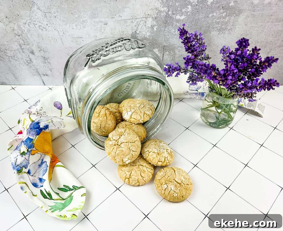 A jar of White Chocolate Crinkle Cookies next to lavender flowers.