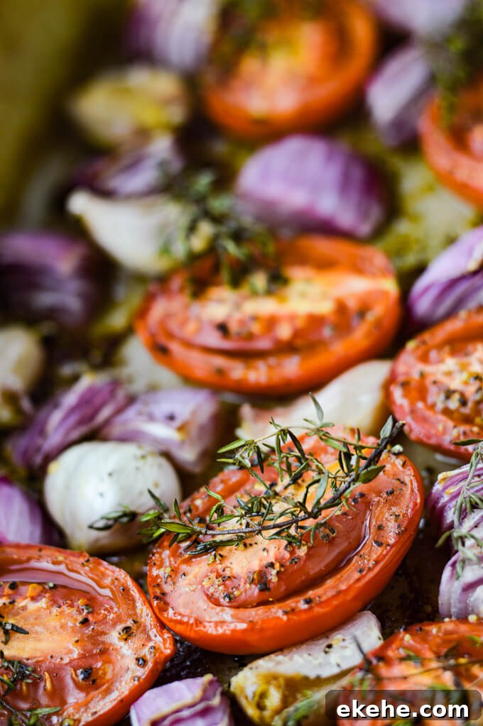 Tomatoes, garlic and red onions and sprigs of thyme are in a stoneware baking pan.
