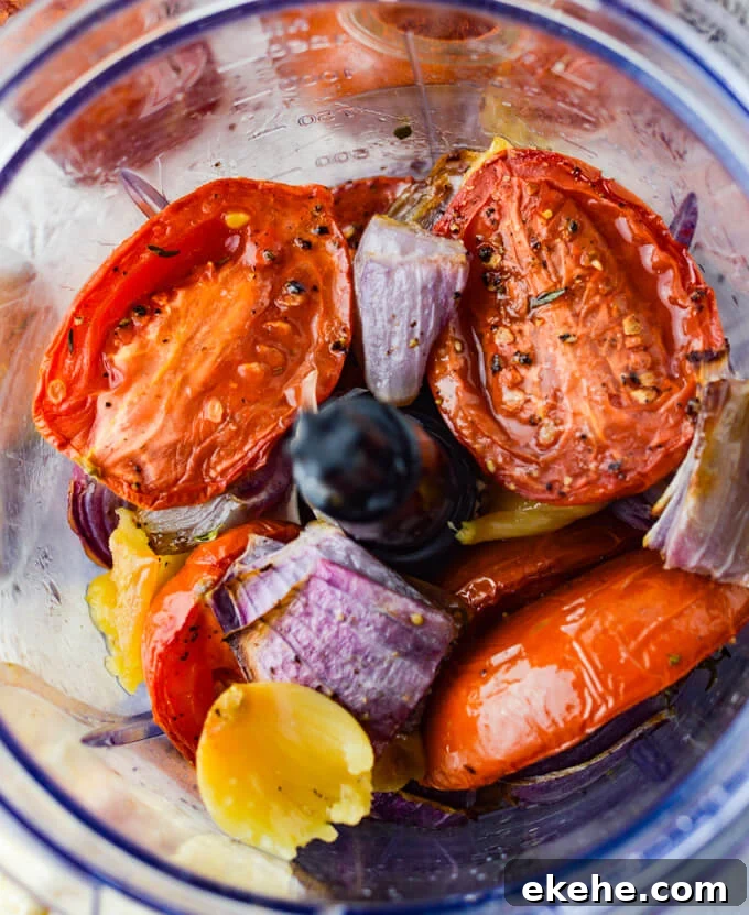 Roasted tomatoes, garlic and red onions are in a food processor.