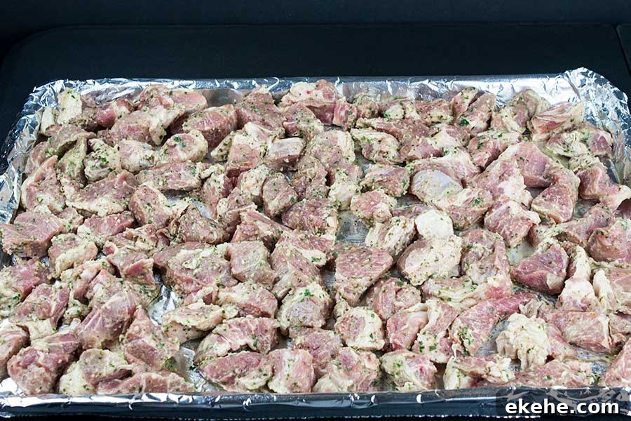 Marinated meat on a foil lined baking sheet.