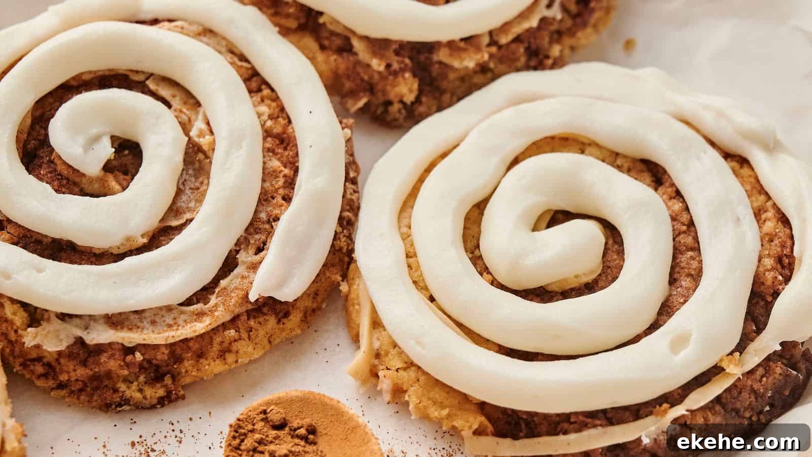 A delectable close-up of Copycat Crumbl Cinnamon Swirl Cookies, adorned with spiral white icing on a parchment paper background.