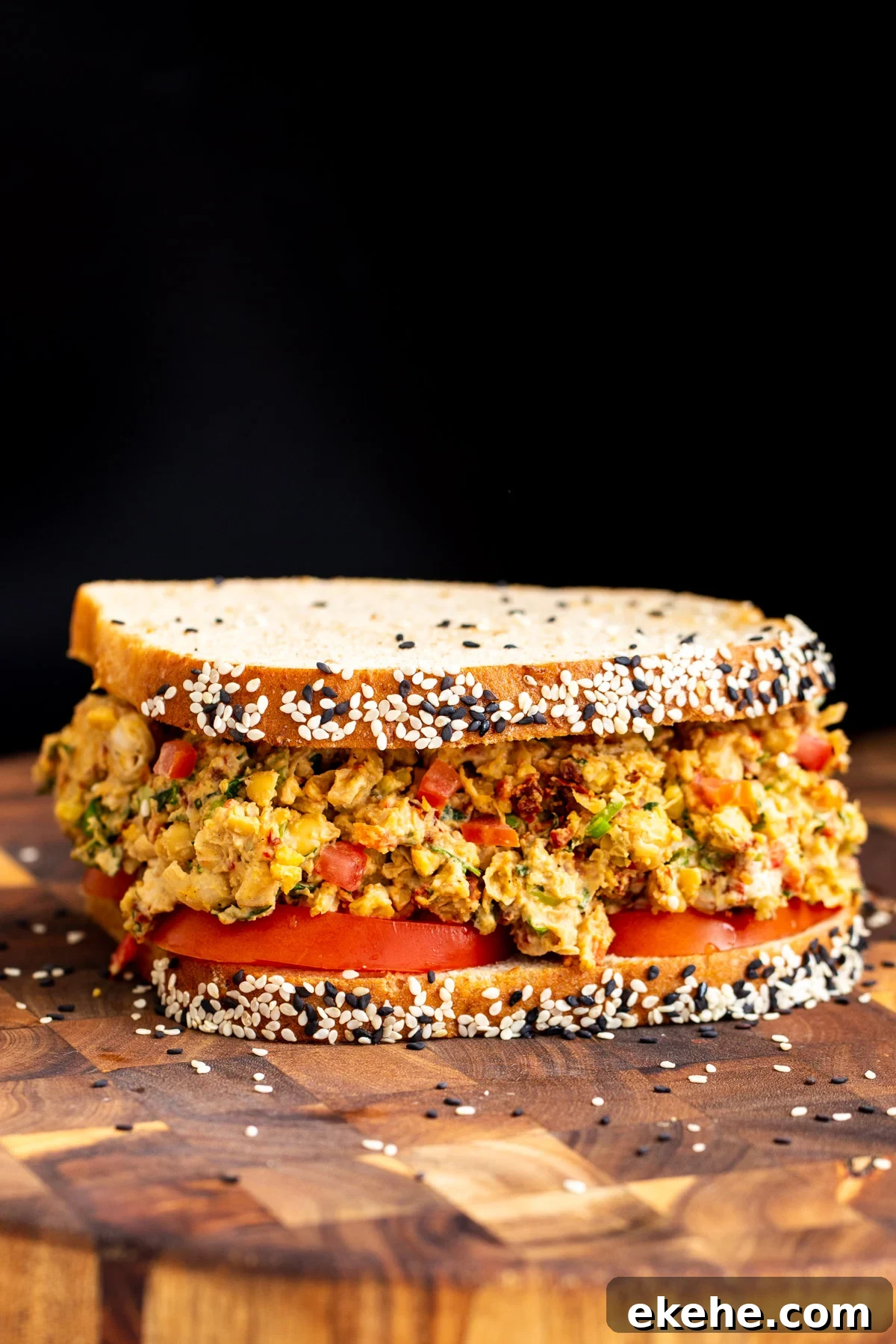 vegan Mediterranean chickpea salad sandwich on multigrain bread served on a wooden board 